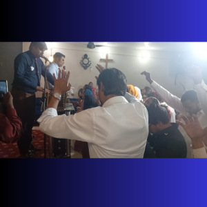 Group of Men with their hands raised as a minister in a blue shirt preaches